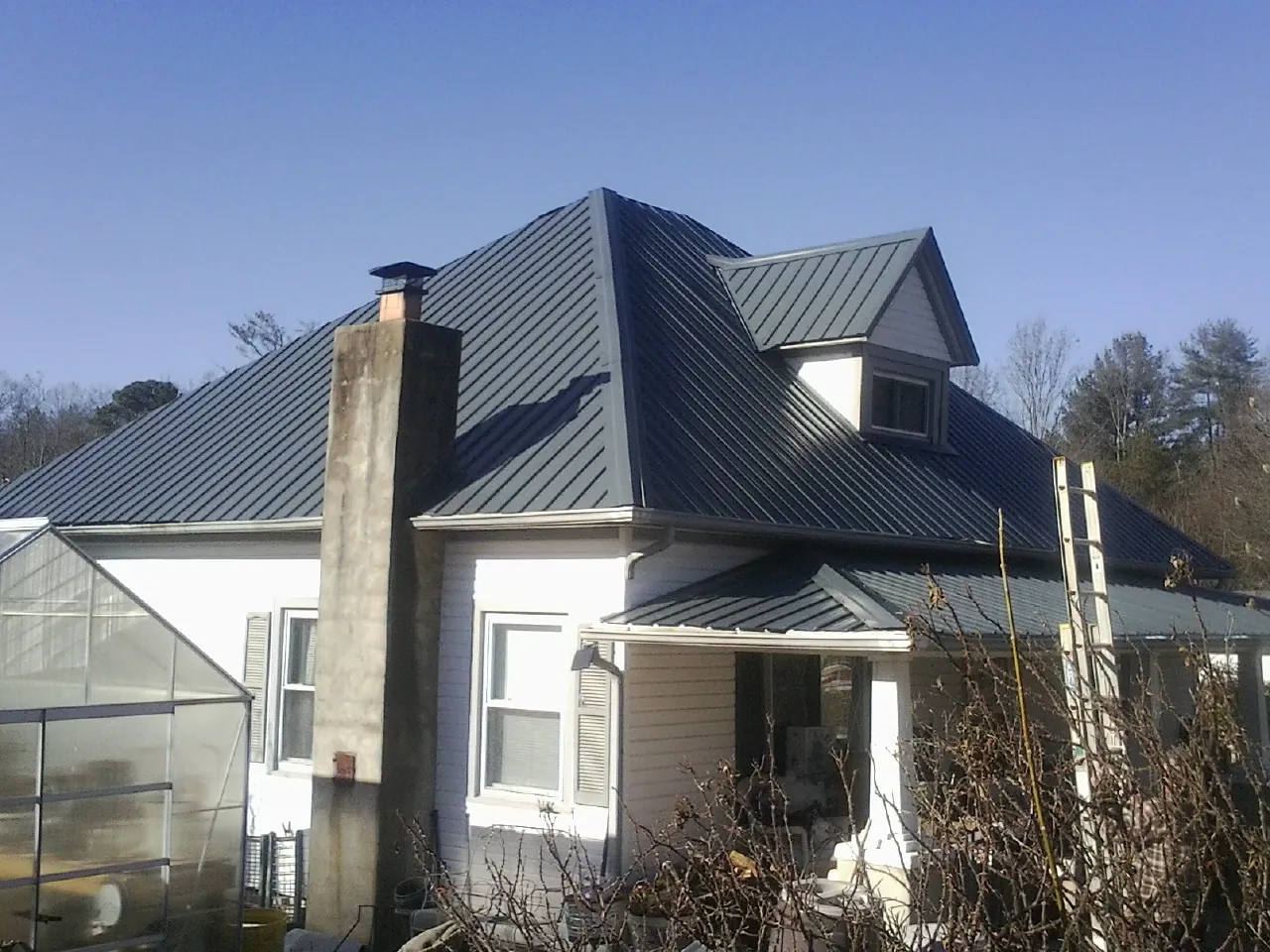 Dark blue standing seam metal roof on a white farmhouse with dormer — Slate & Tile Roof Repair by Roofing Brothers in Bala Cynwyd