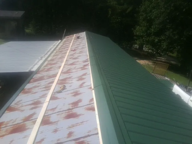 Old rusted panels beside newly installed green metal roofing — Wind Damage Roof Repair by Roofing Brothers in Bala Cynwyd