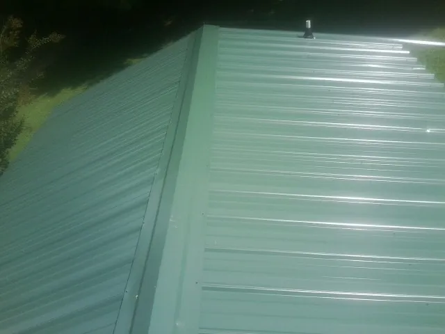 New green metal panels meeting at the ridge of a roof — Flat Roof Repair work by our crew in Bala Cynwyd