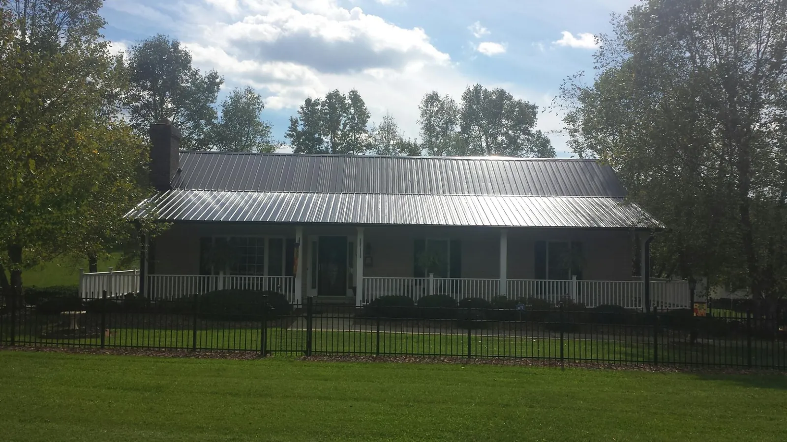 Gray metal roof on a brick ranch with a full width front porch — Gutter Guard Installation work by our crew in Bala Cynwyd