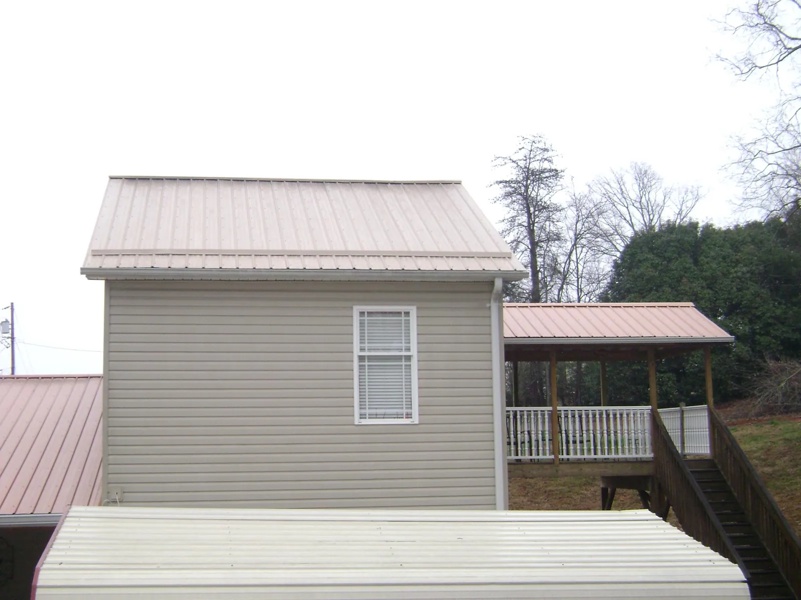 Tan metal roofs on a two story addition and attached porch, from a Roof Replacement job in Bala Cynwyd