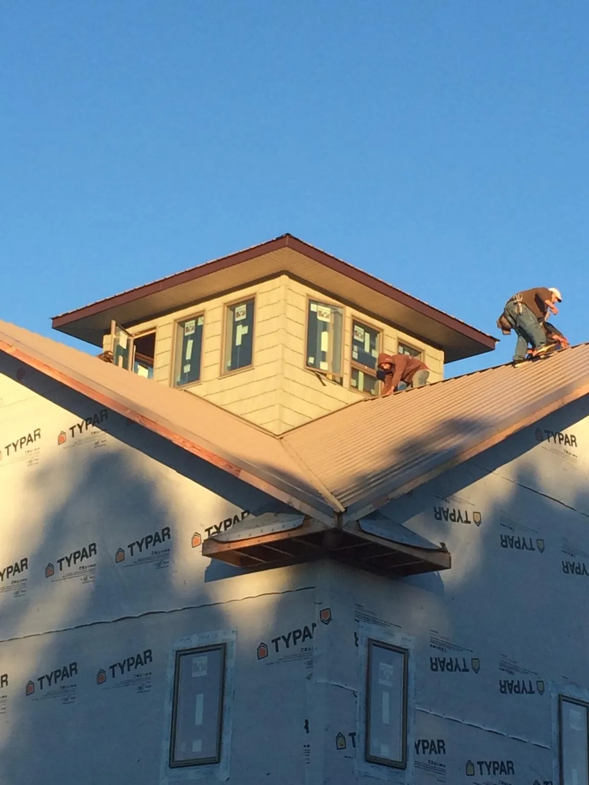 Roofers working around a rooftop cupola on a new metal roof at sunset — Roof Waterproofing in Bala Cynwyd by Roofing Brothers